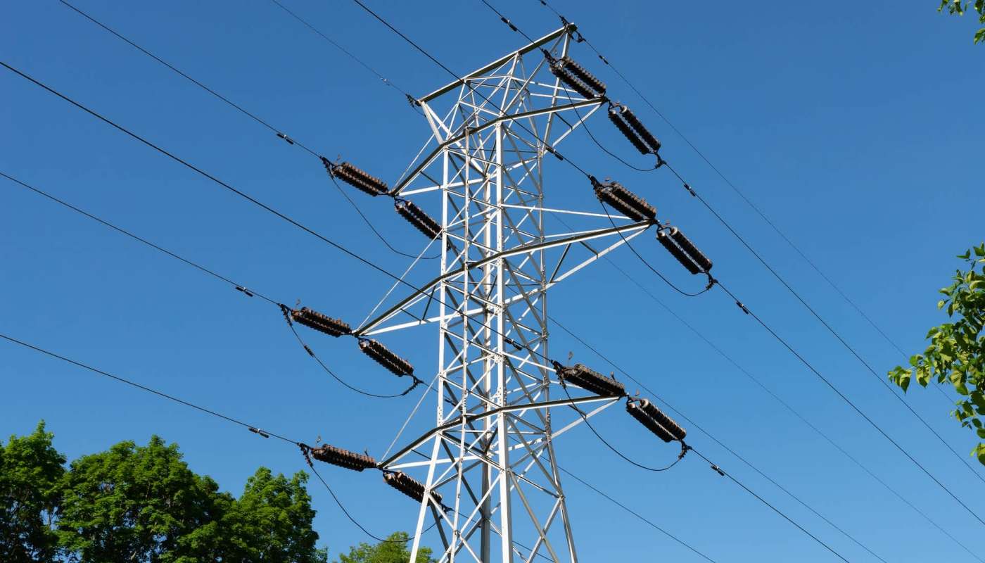 A tall electrical transmission tower with numerous wires against a clear blue sky.