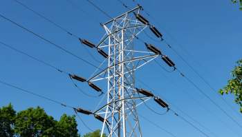 A tall electrical transmission tower with numerous wires against a clear blue sky.