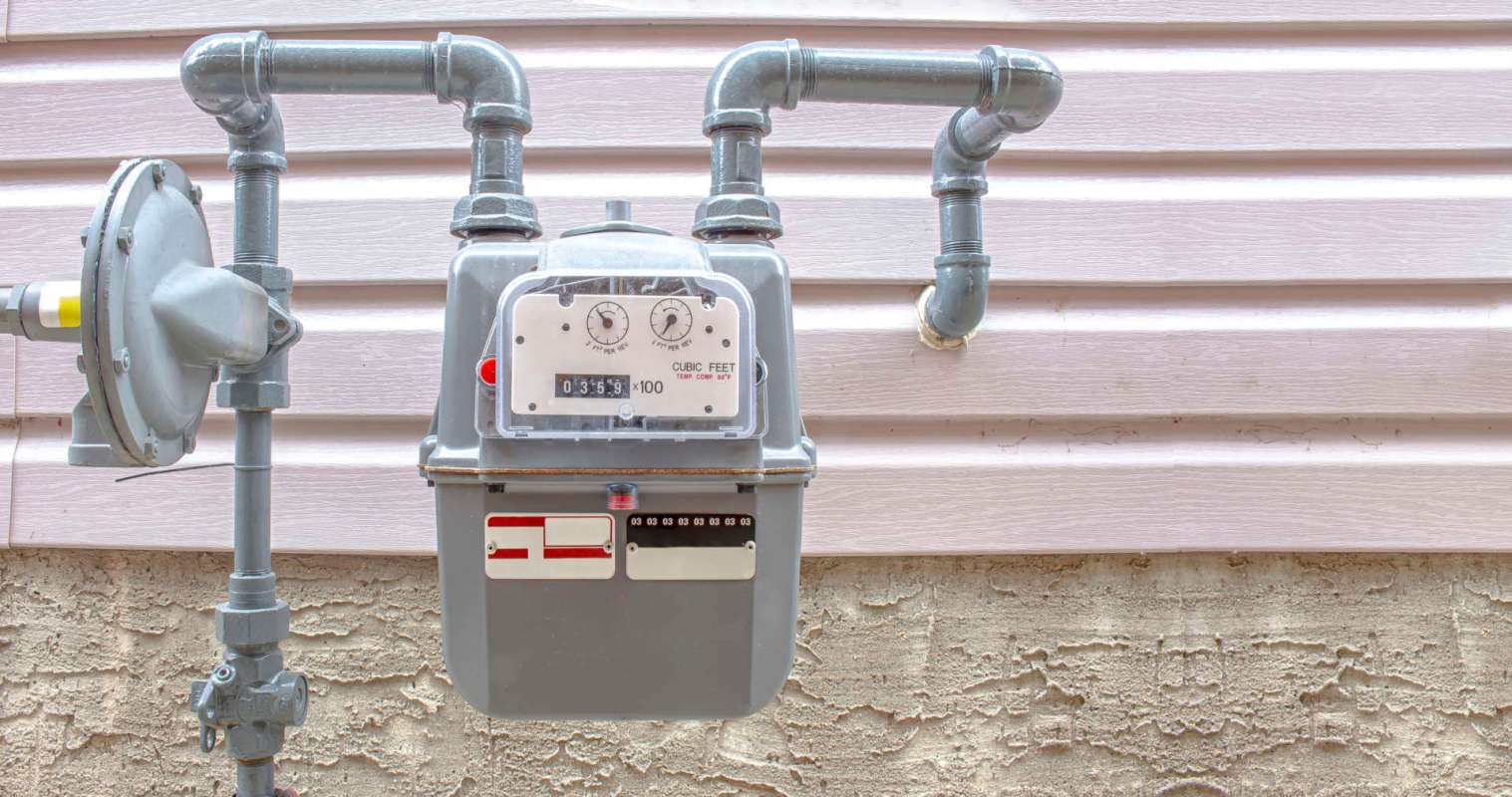 A gas meter with pipes attached, mounted on a wall.