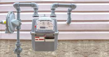 A gas meter with pipes attached, mounted on a wall.