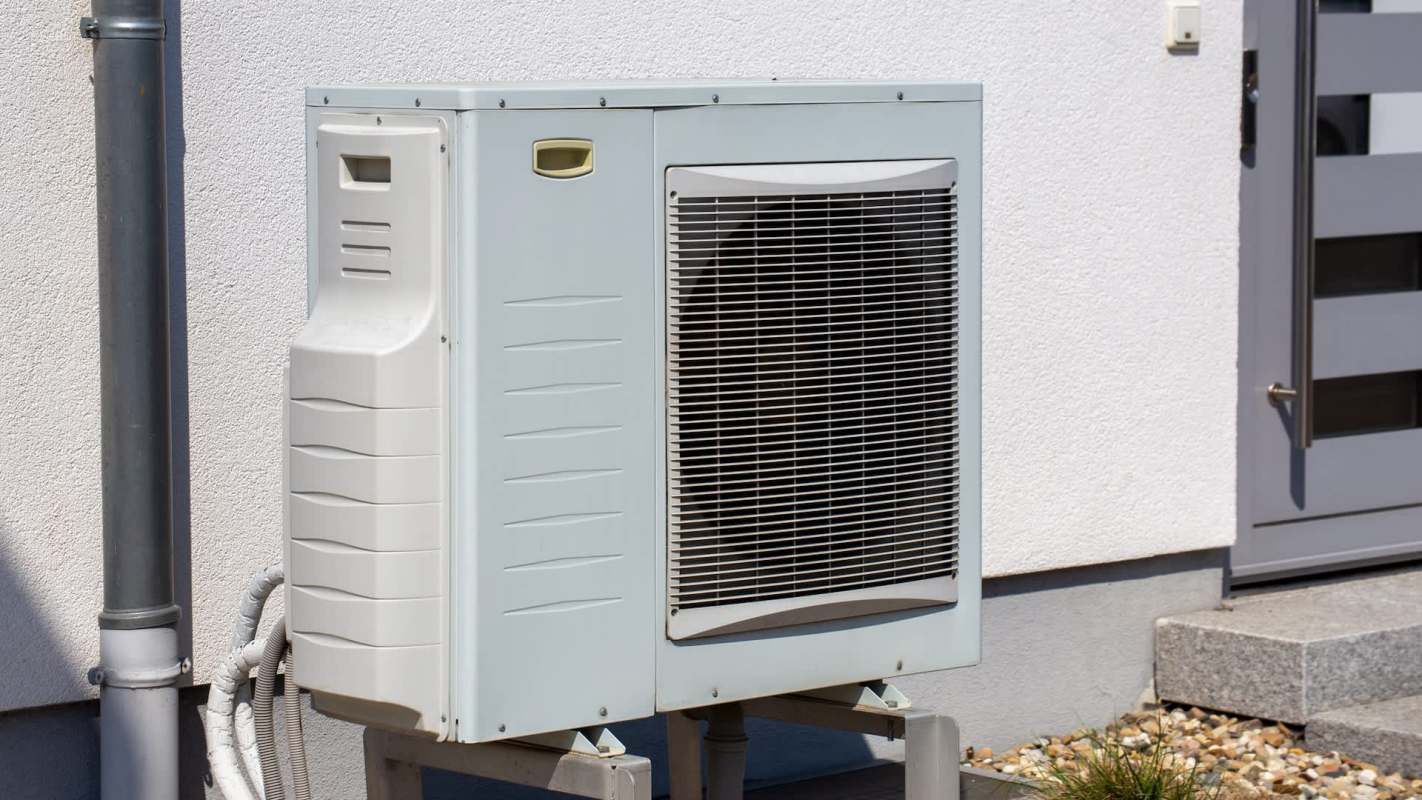 An outdoor air conditioning unit next to a wall and a set of steps.