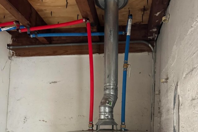 A metal pipe with red and blue water supply lines.