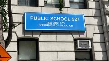 A blue sign displaying "PUBLIC SCHOOL 527" on a building exterior in New York City.