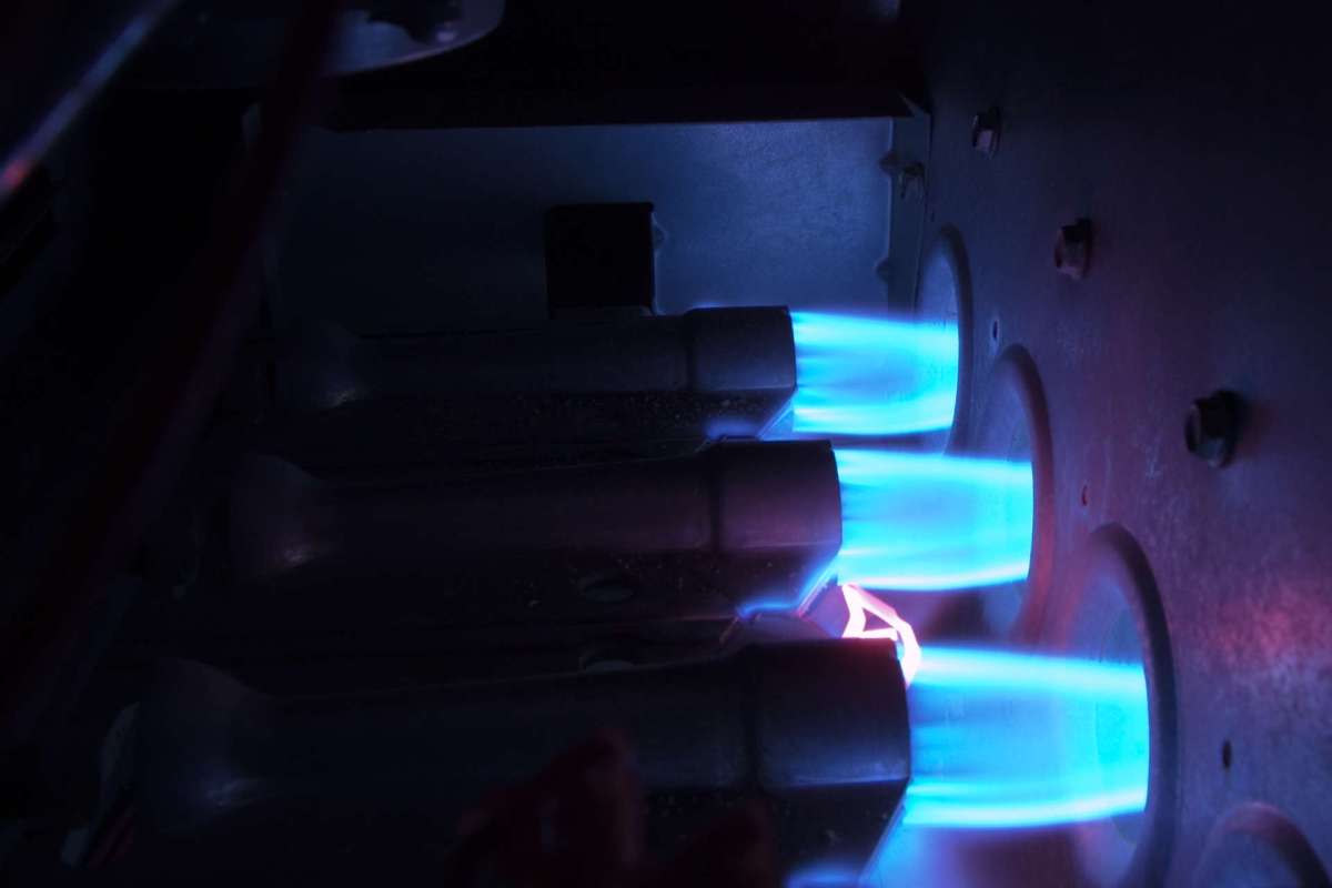Blue flames are visible through gas burners in a dark environment.