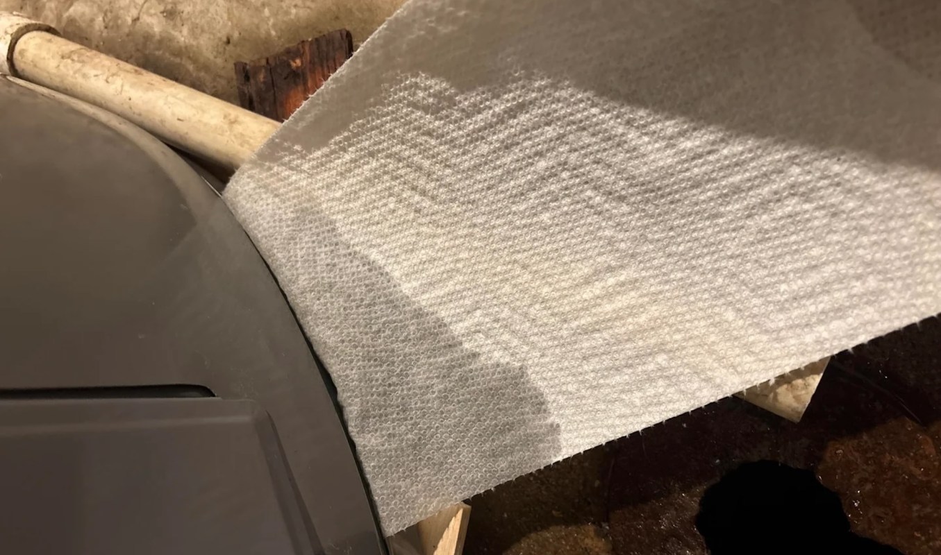A paper towel is positioned near a metal container and a wooden surface.
