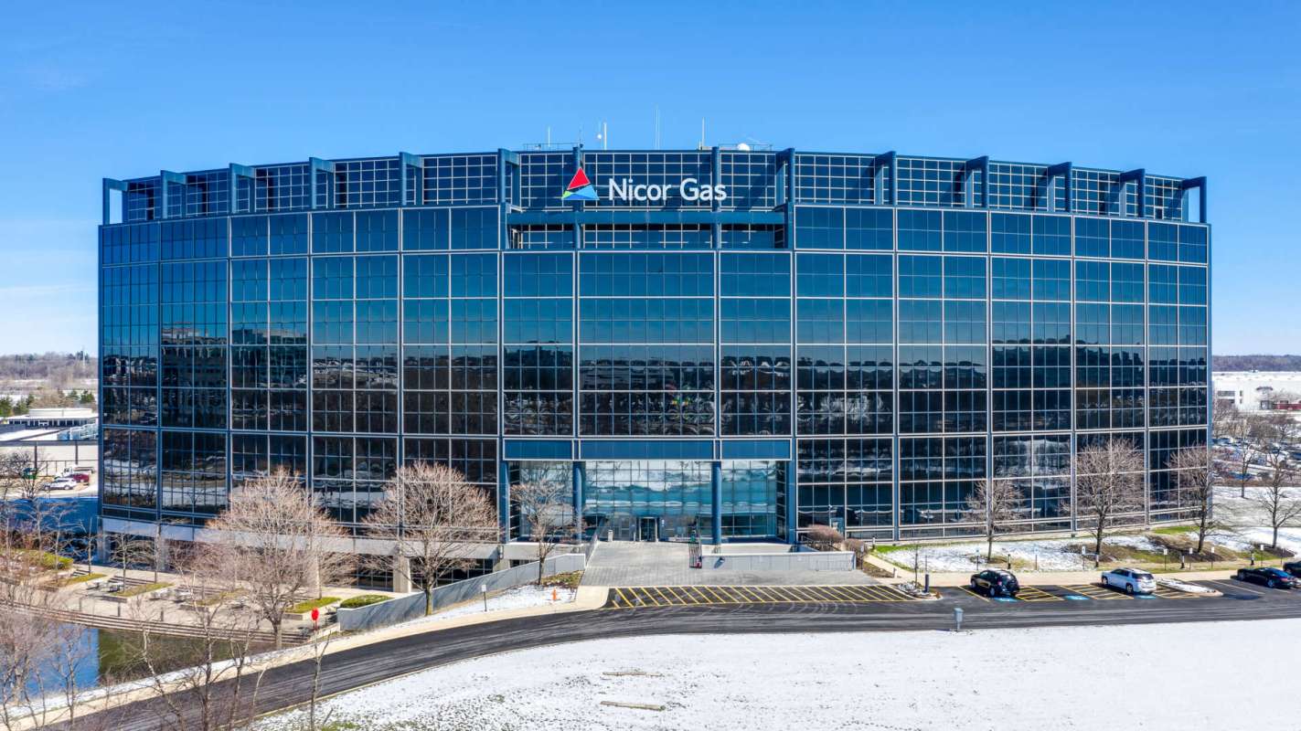 A modern office building with reflective glass windows and a sign for Nicor Gas.