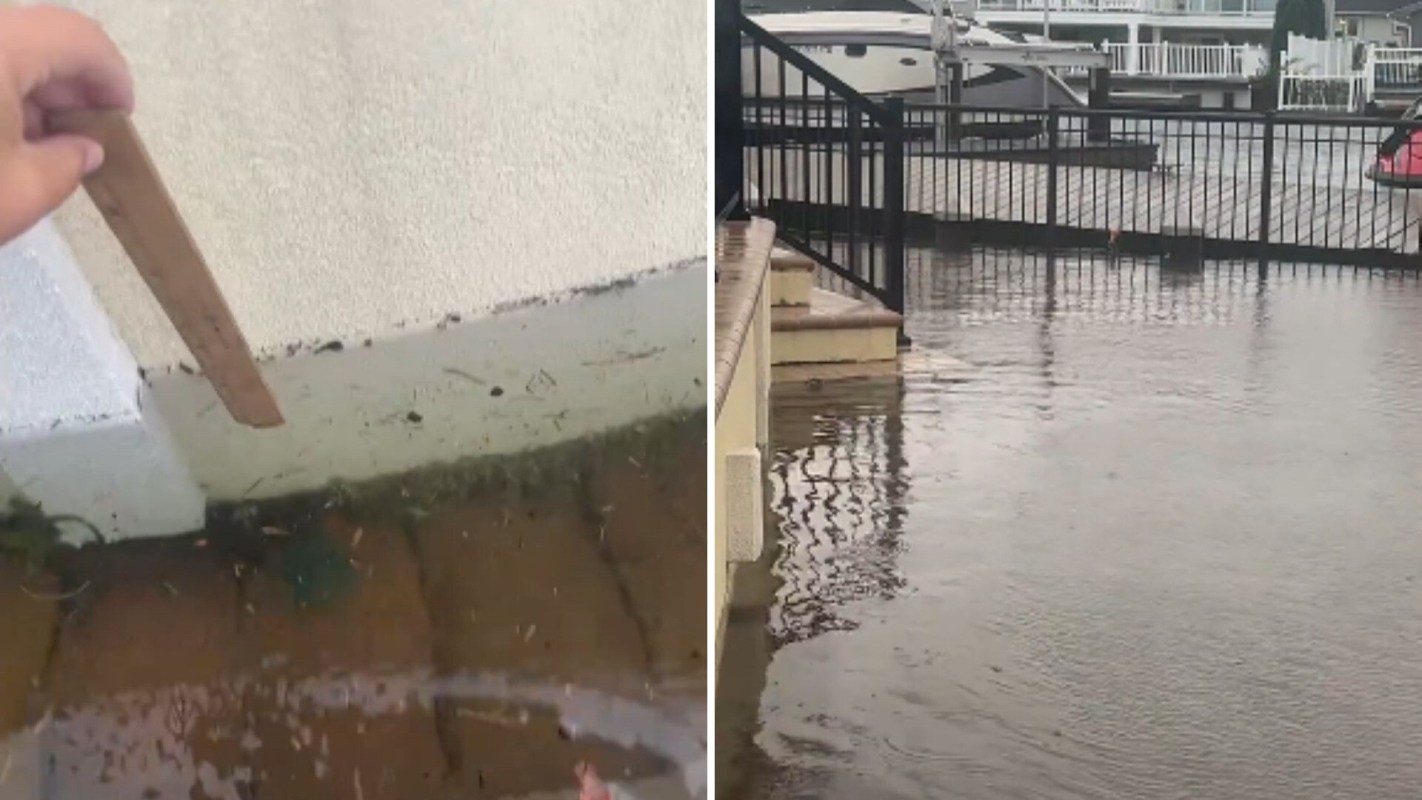 A person showing and measuring floodwater.