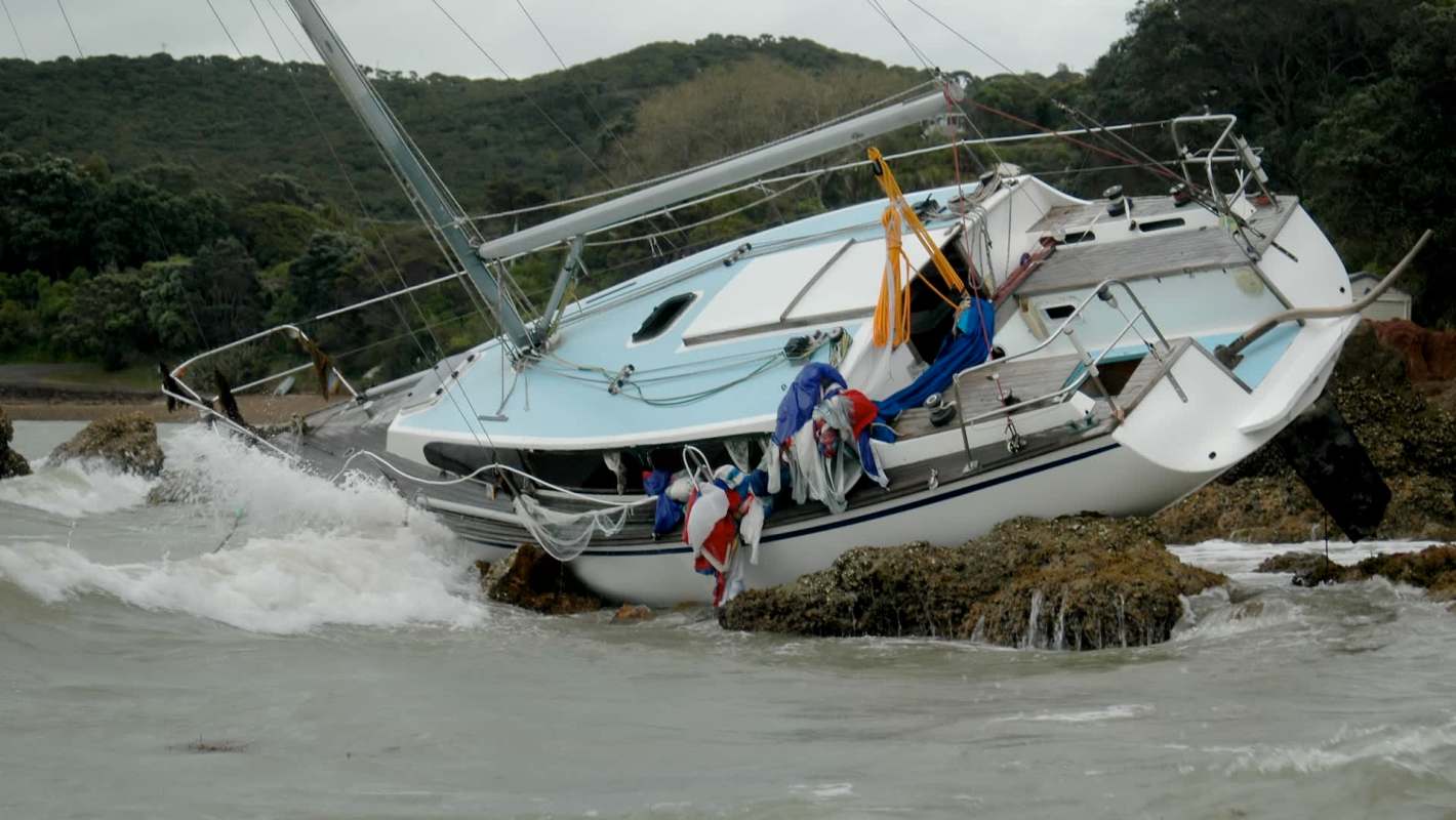 A sailboat partially stranded on rocks.