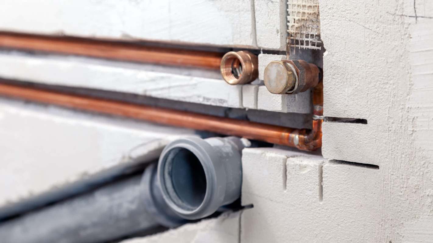 Copper and plastic pipes connected to a wall with visible joints and fittings.