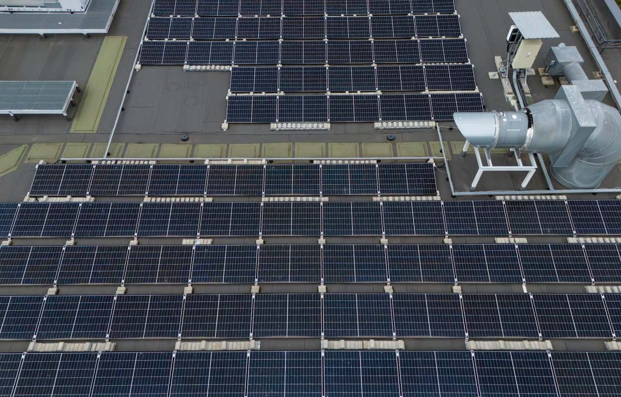 A rooftop covered with solar panels and an industrial ventilation system.