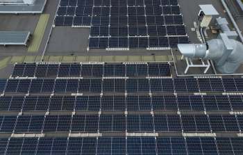 A rooftop covered with solar panels and an industrial ventilation system.