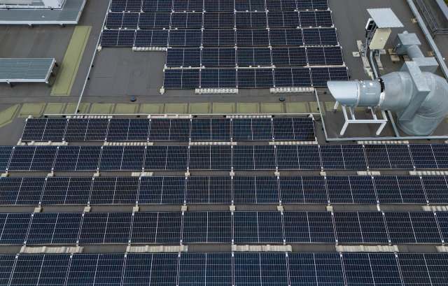 A rooftop covered with solar panels and an industrial ventilation system.
