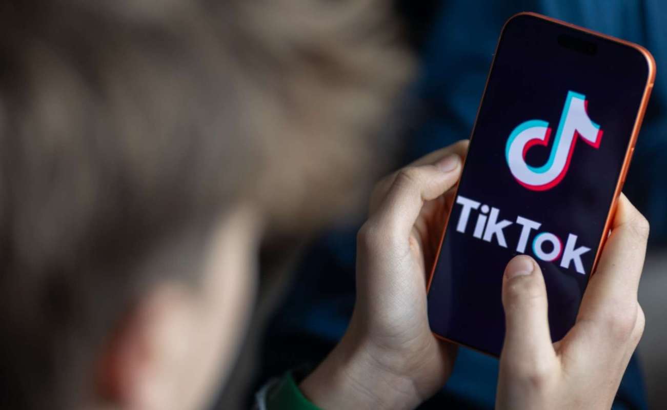 A person holds a smartphone displaying the TikTok logo.