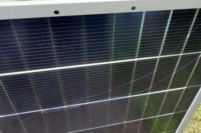 A solar panel with visible cracks and dirt on the surface.