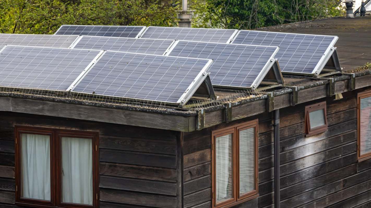 Solar panels installed on the roof of a wooden building with windows.