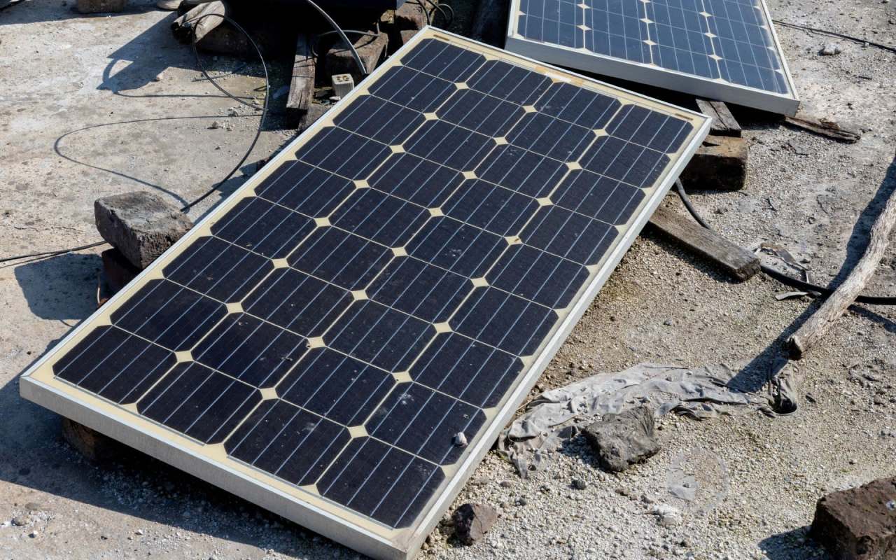 Two solar panels are placed on the ground, surrounded by rocks and debris.