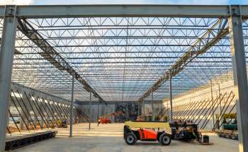 An empty construction site with machinery and a steel frame overhead.