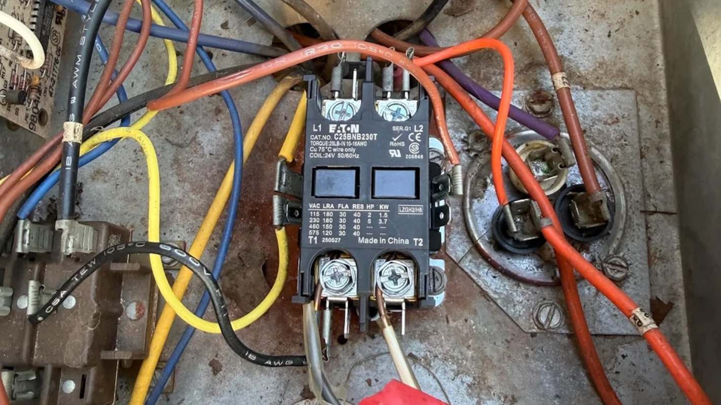 A power relay with multiple colored wires connected to it in a rusted metal housing.
