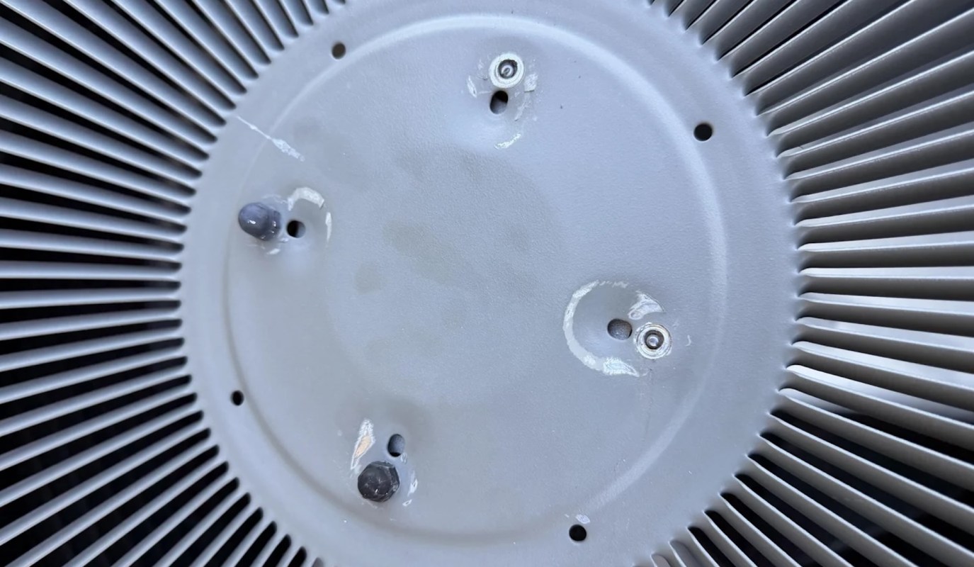 A circular metal surface with screws and ridges, showing signs of wear and imperfections.