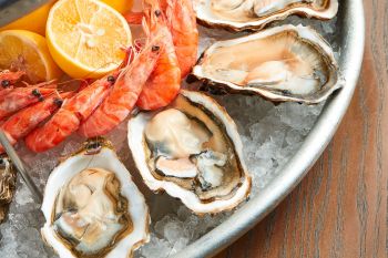 An array of shrimp and oysters sit on a bed of ice