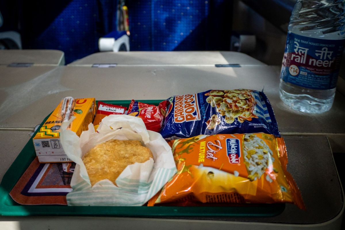 A food tray with snacks, including a packaged drink, popcorn, and a fried item.