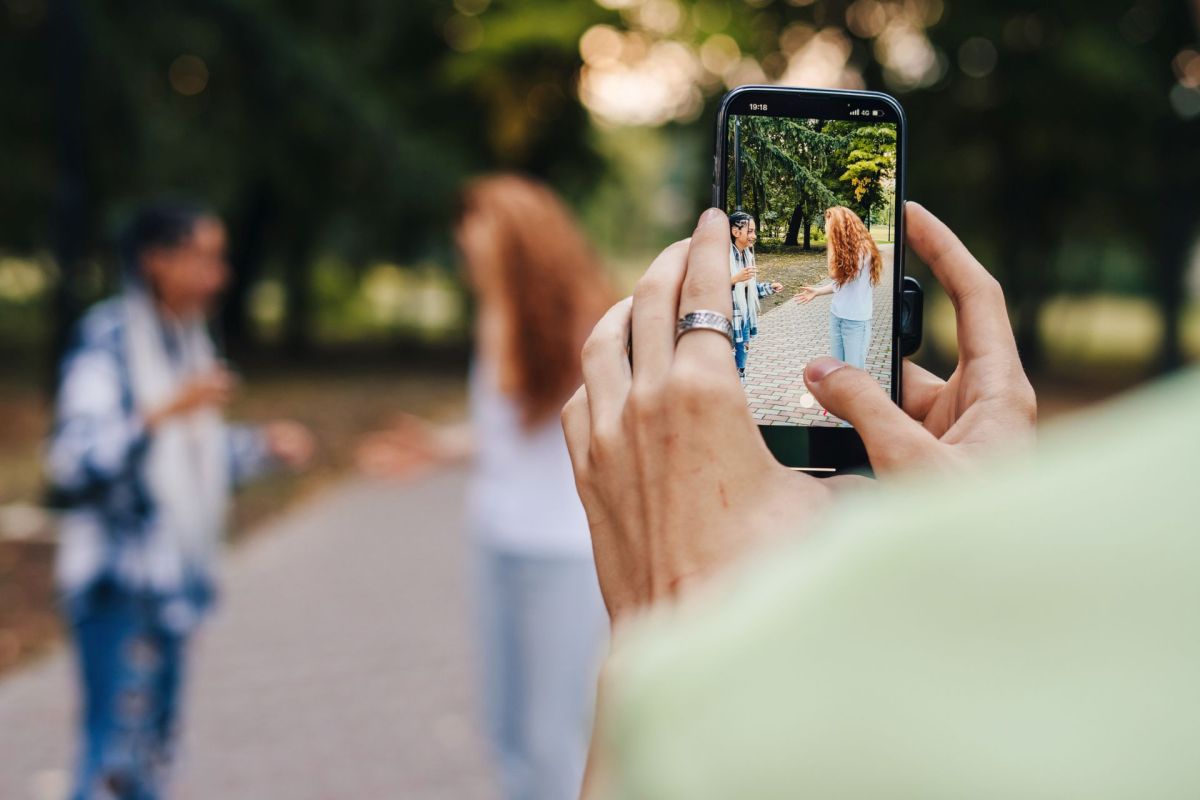 A person taking a video of two people in a park.