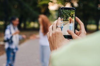 A person taking a video of two people in a park.
