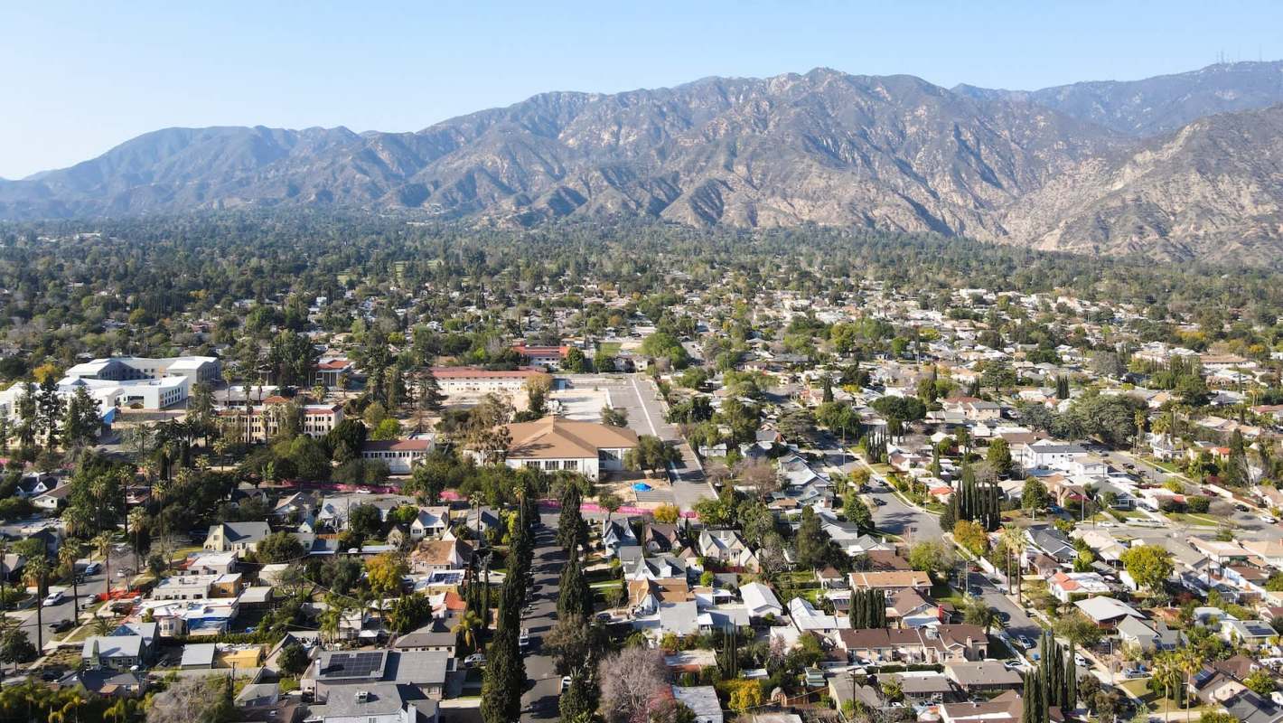 Aerial view of Pasadena, California, with houses and mountains in the background.