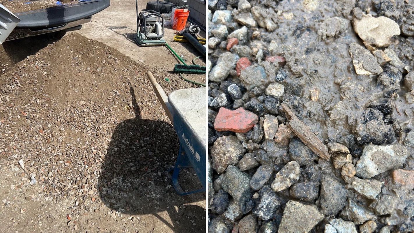 A pile of gravel and a wheelbarrow next to a wet patch of ground with small stones and debris.