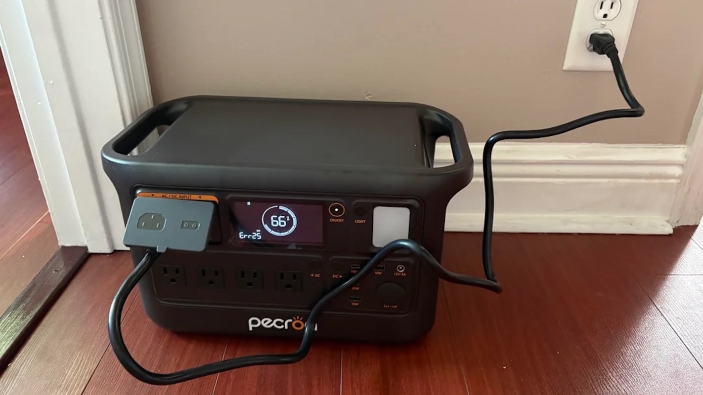 A portable power station plugged into a wall outlet with a digital display showing error and battery status.