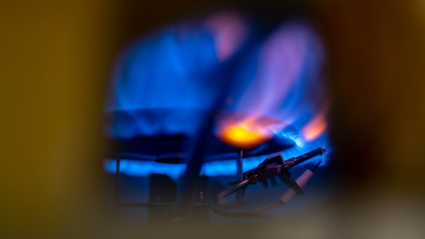 A gas burner with a blue flame and ignition components.