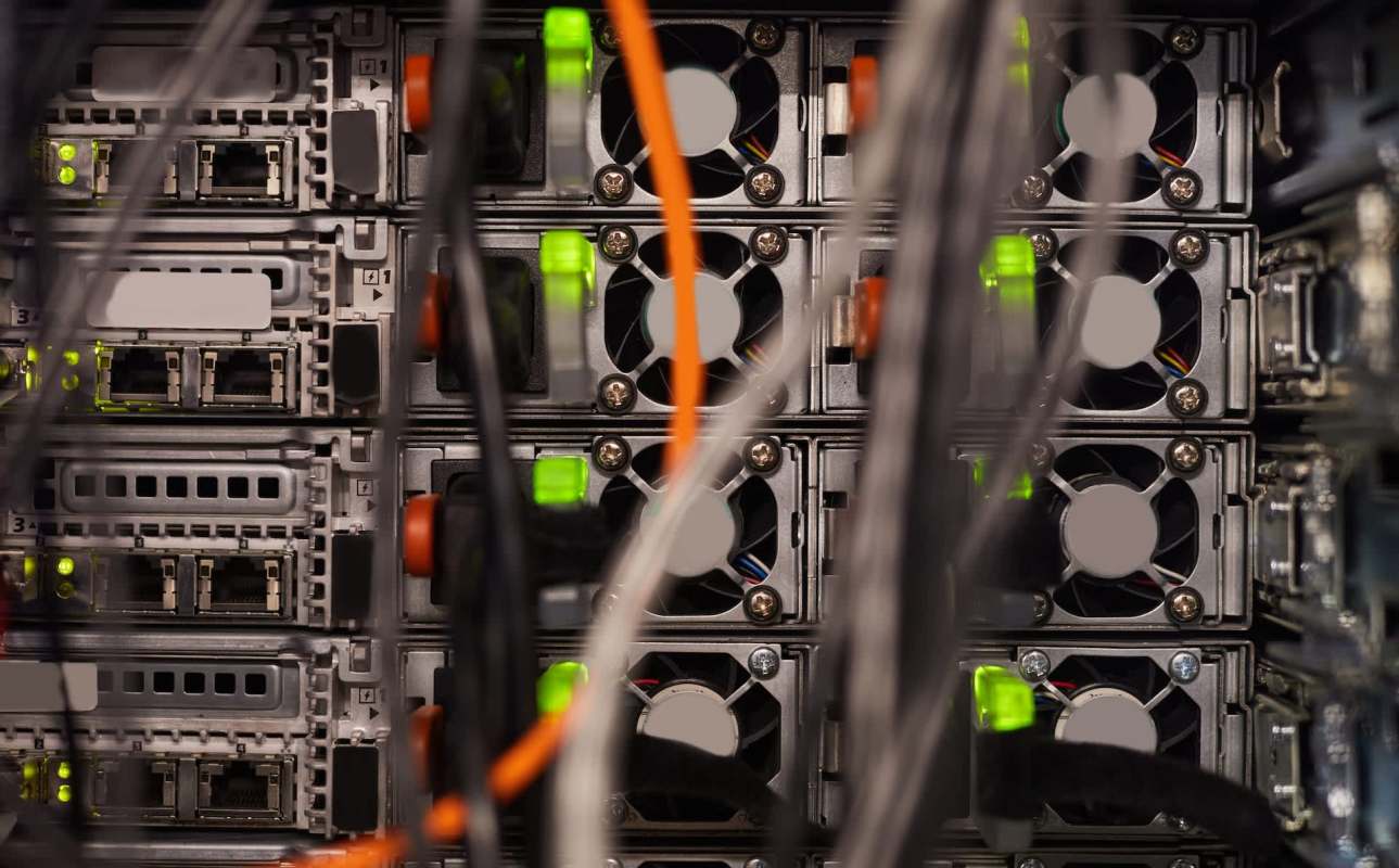 A row of server units with illuminated indicators and tangled wiring.