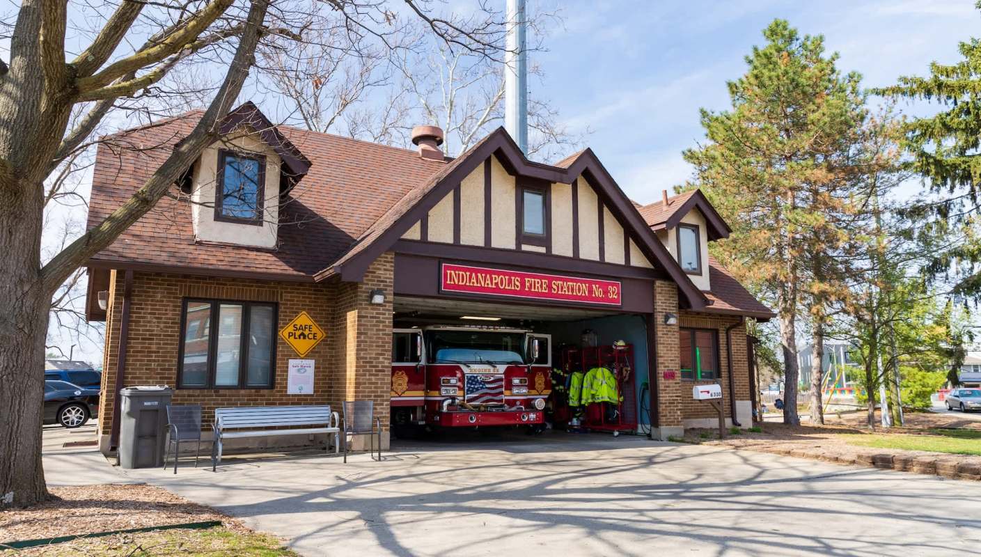 A fire station with a fire truck parked outside and safety signage visible.