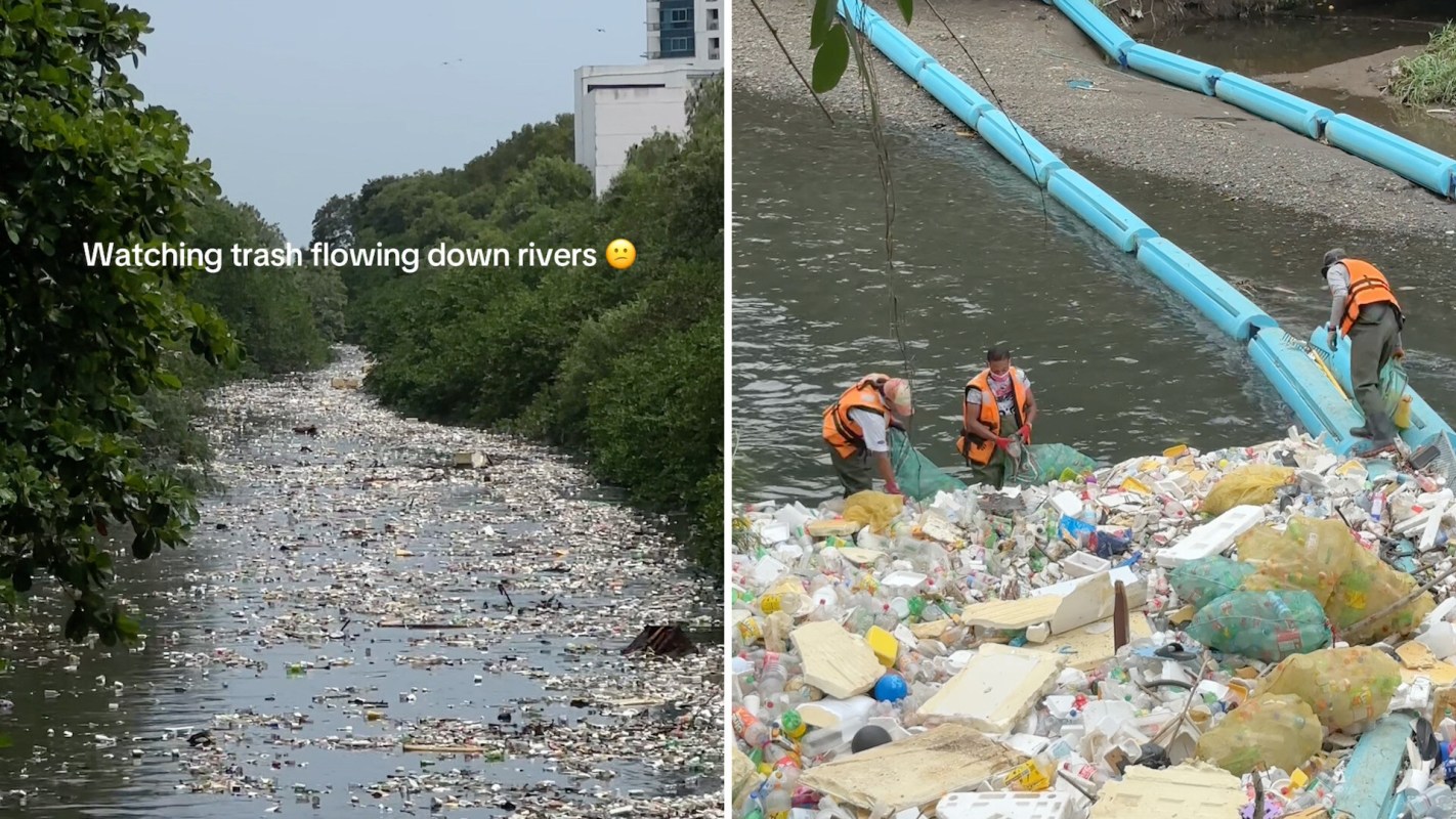 A river filled with trash and two workers in vests collecting debris from a pile.