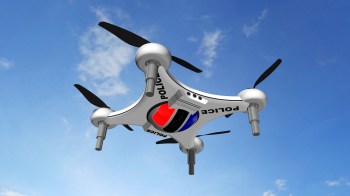 A police drone flying against a clear blue sky.