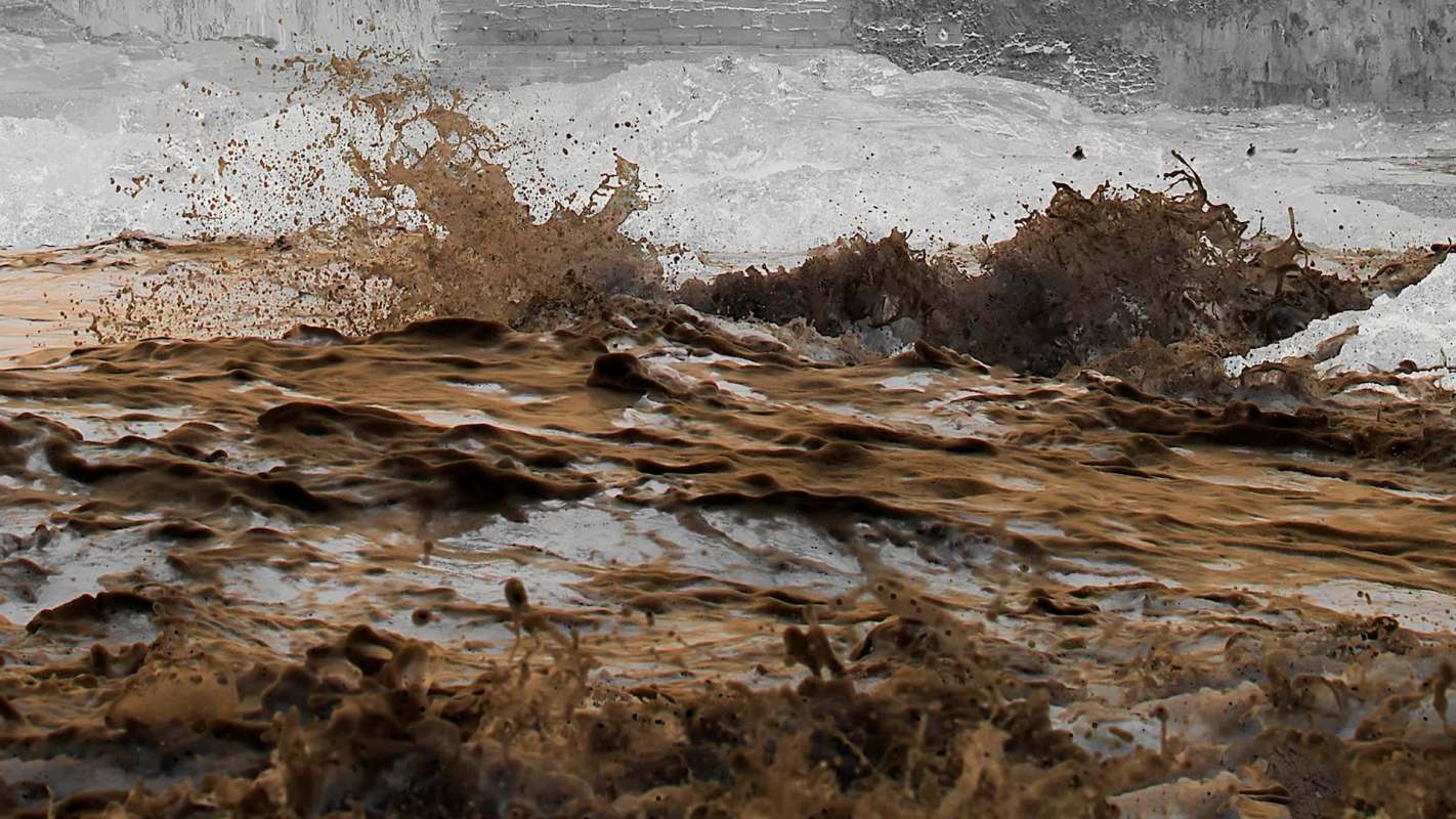 Mud and water splashing violently, creating waves and foam in a turbulent scene.