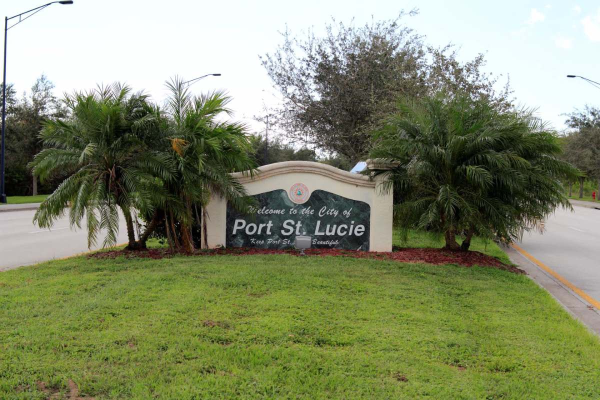 A welcome sign for the city of Port St. Lucie surrounded by palm trees and grass.
