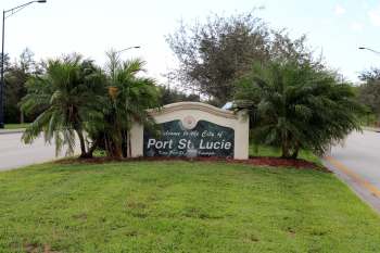 A welcome sign for the city of Port St. Lucie surrounded by palm trees and grass.