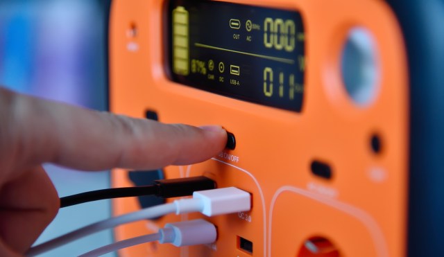 A hand presses a button on a portable power station.