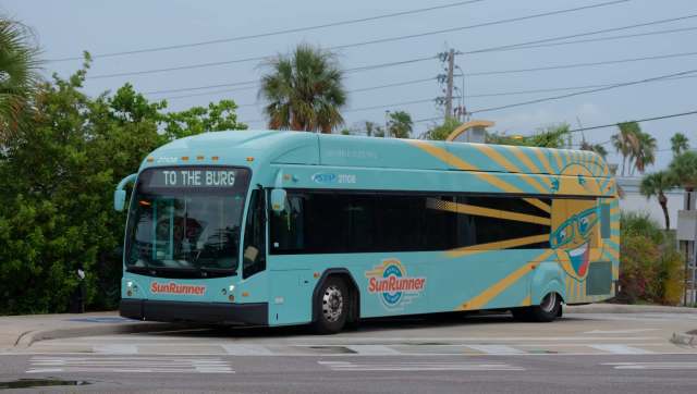 A hybrid electric bus with a colorful design, displaying "TO THE BURG" on its front sign.