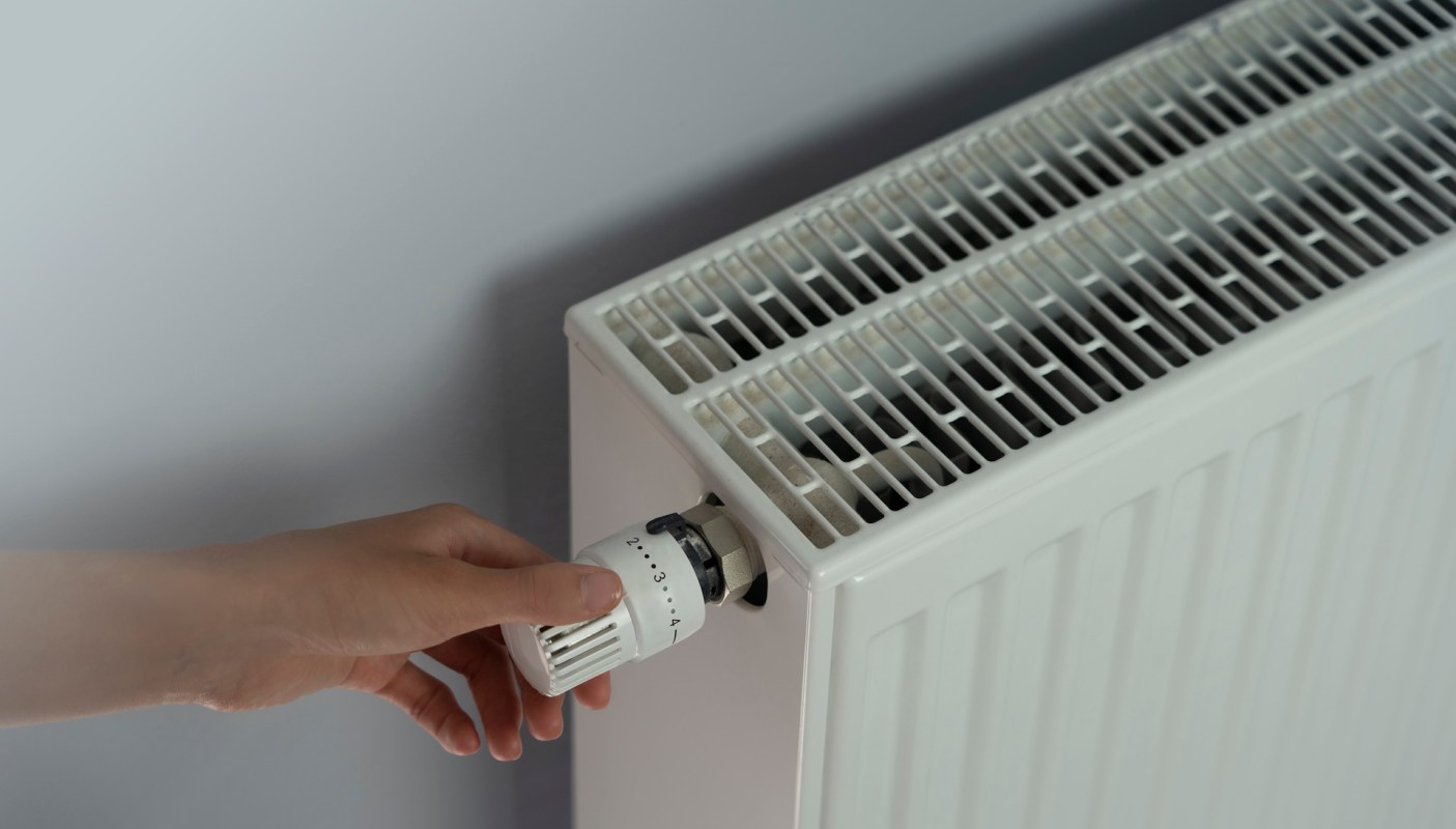 A person adjusting a radiator's temperature.