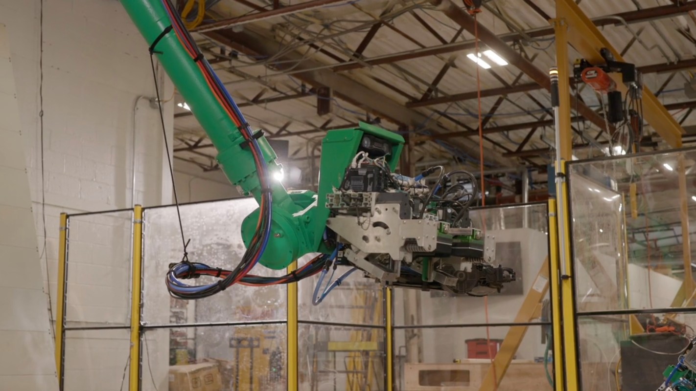 A robotic arm with various cables is seen in an industrial setting.