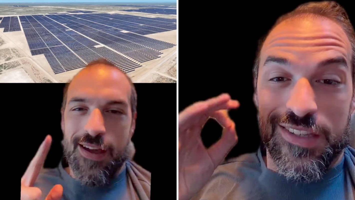 A man speaks while an aerial view of a solar panel installation is displayed behind him.