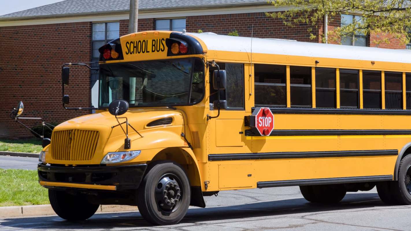 A yellow school bus on a residential street with a stop sign extended.