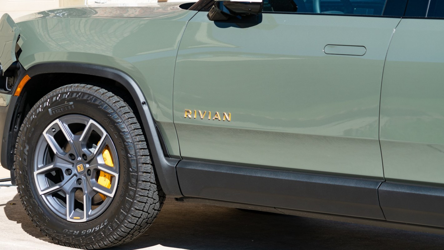 A green Rivian electric vehicle with a visible wheel and door handle.
