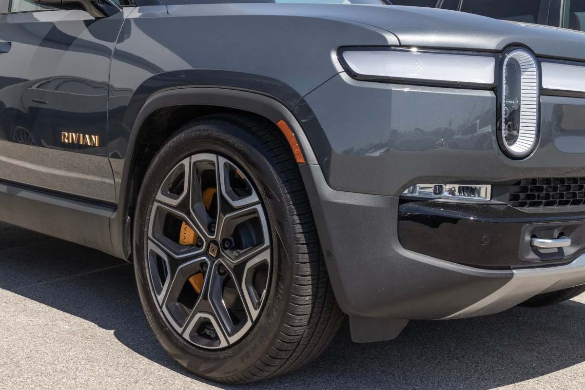A close view of a gray Rivian electric vehicle's front side and wheel.