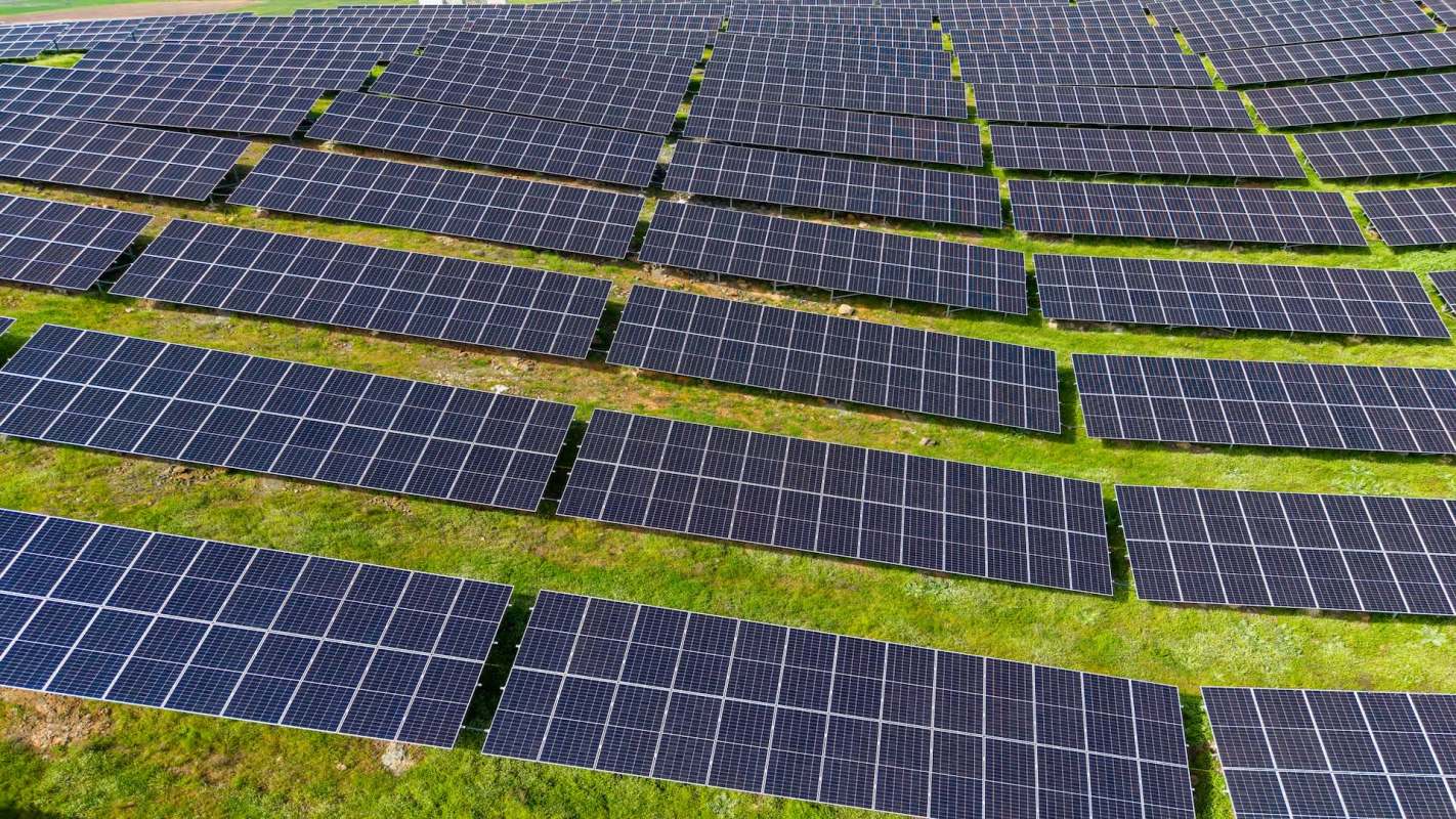 Aerial view of solar panels arranged on green grass.