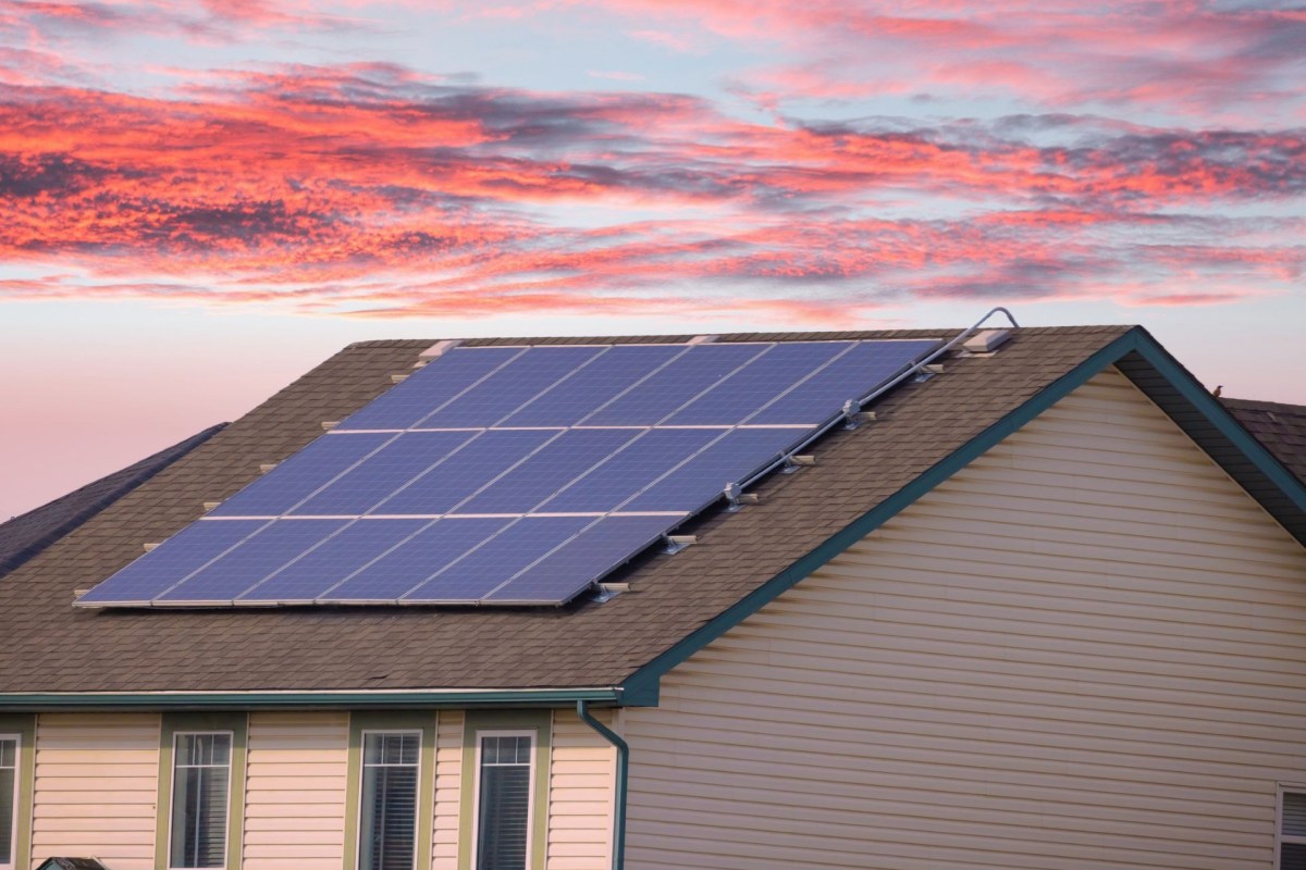 A house with rooftop solar panels at sunset.