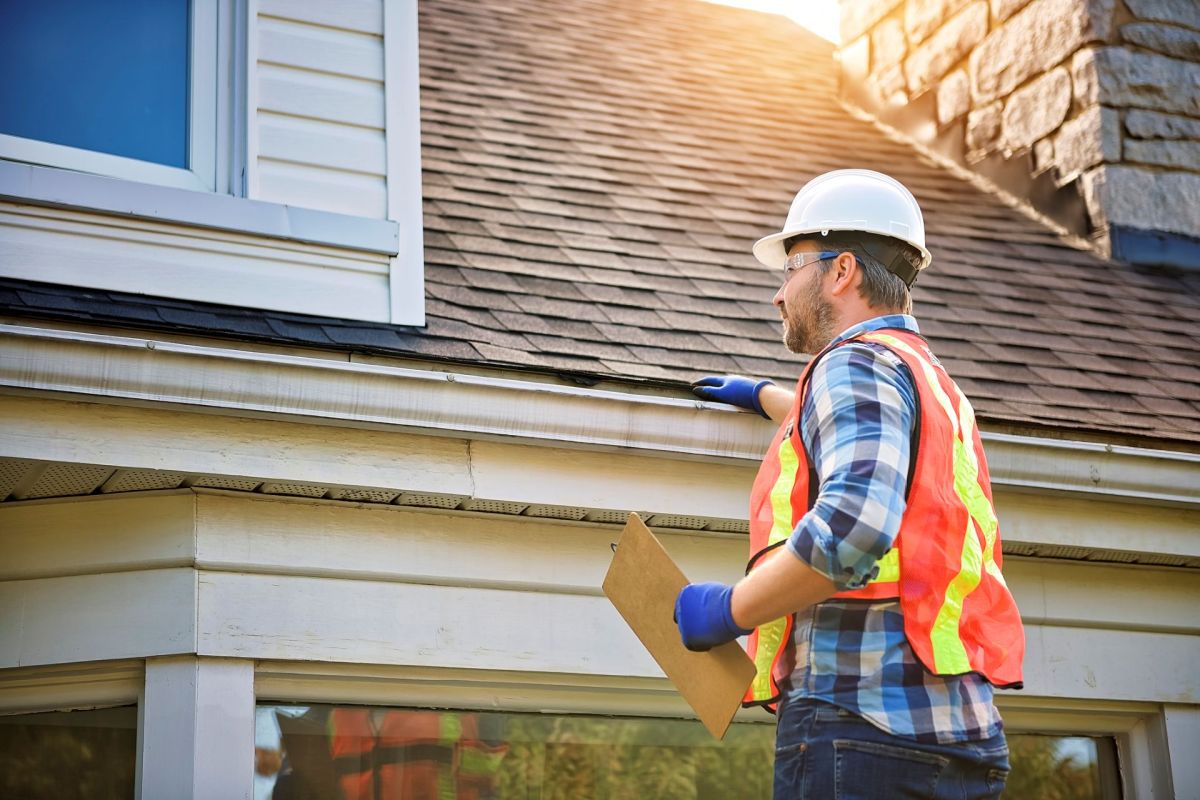 A man conducting a roof inspection on a house.