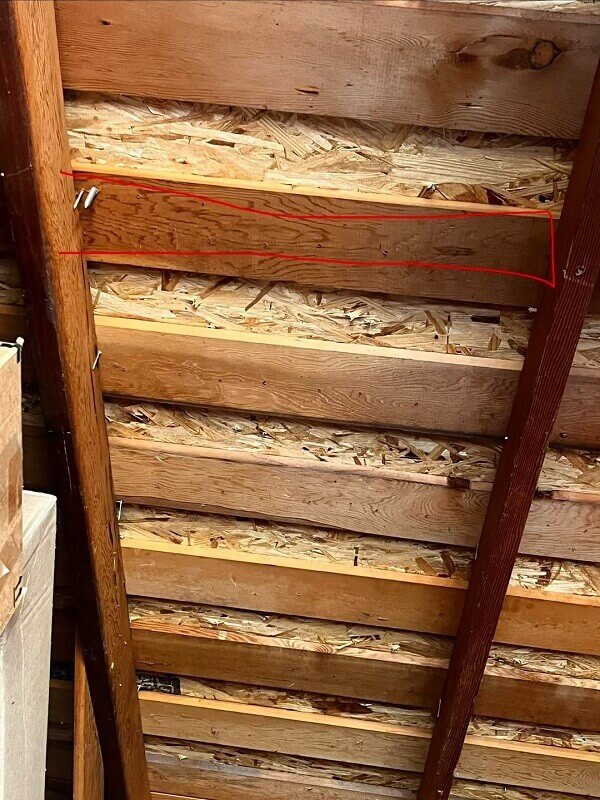A view of wooden rafters in a garage with visible bracket locations.
